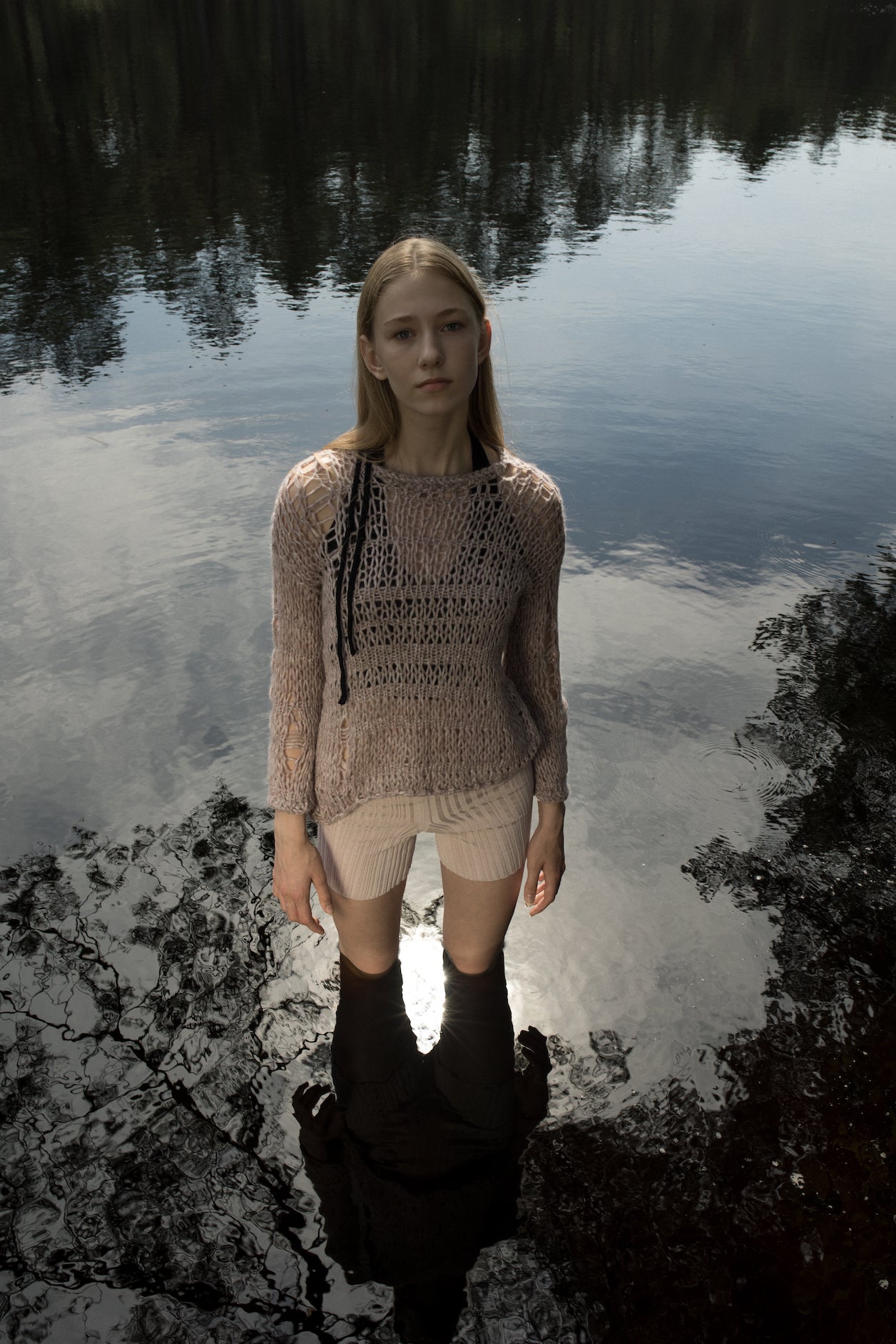 Model wearing an open-knit alpaca pullover layered over a bra top